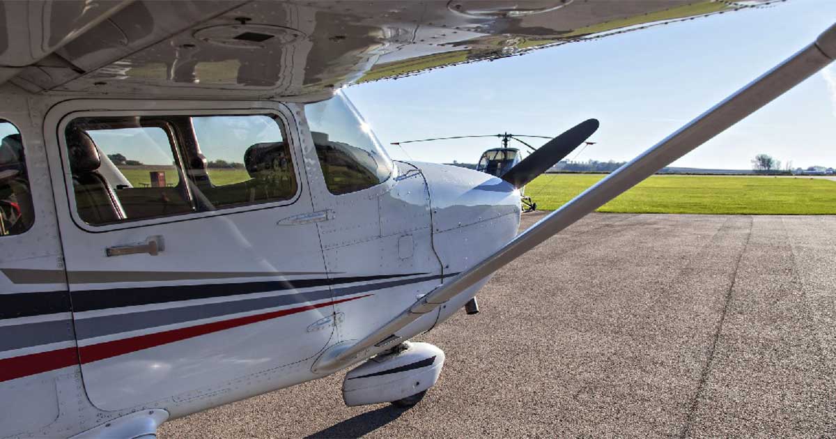 Small airplane on tarmac facing towards a bright field